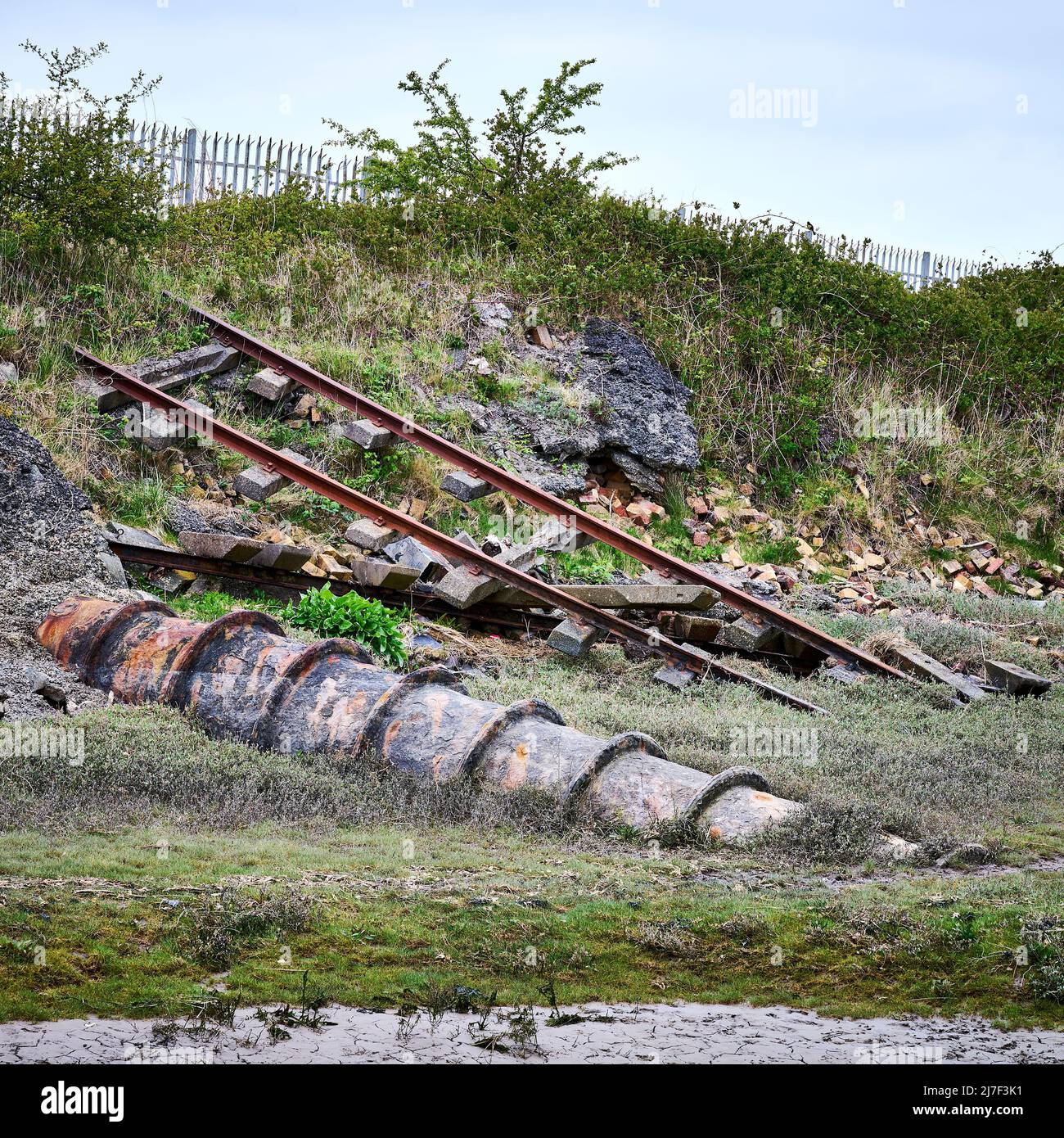 Eaux usées industrielles. La maçonnerie de bâtiment sous-évaluée et une ancienne voie ferrée à côté d'un tuyau inutilisé Banque D'Images