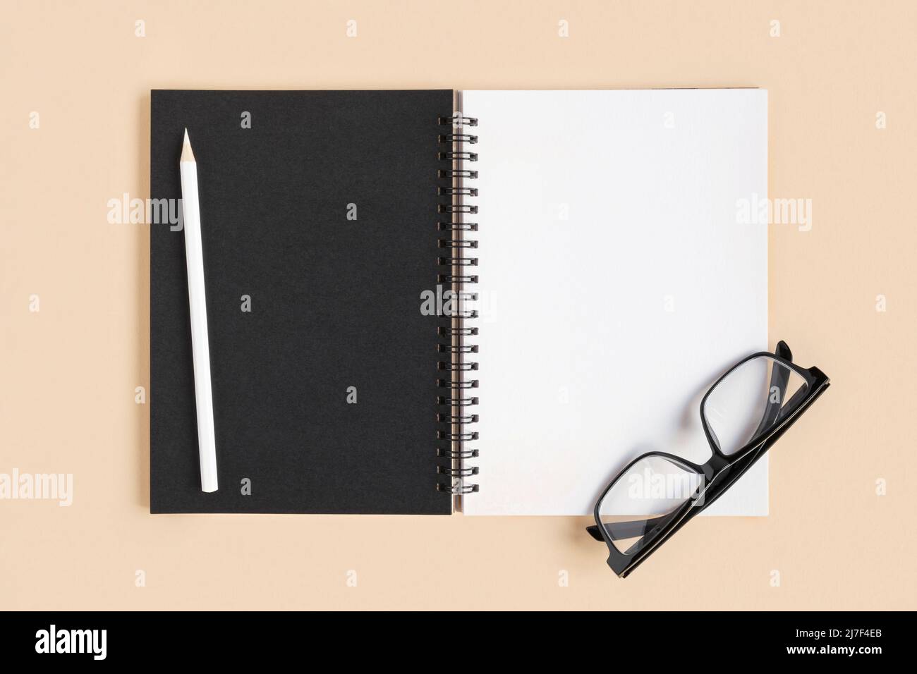 Carnet avec crayon. Ouvrez le bloc-notes sur fond beige, le bloc-notes de bureau en spirale sur une table avec des pages vierges. Vue de dessus. Page blanche pour l'écriture. Banque D'Images