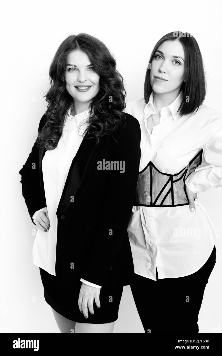 Gros plan portrait élégant magnifiques femmes portant un costume de luxe tendance, regardez l'appareil photo, souriant. De belles femmes d'affaires en tenue habillée s'assoient Banque D'Images