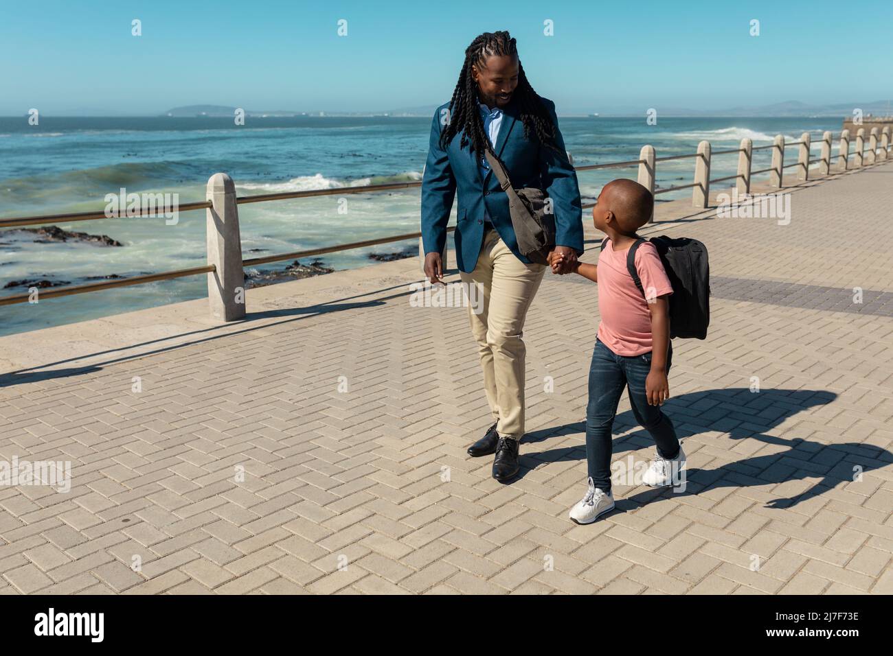 Pleine longueur de père et fils afro-américains tenant les mains tout en appréciant la promenade Banque D'Images