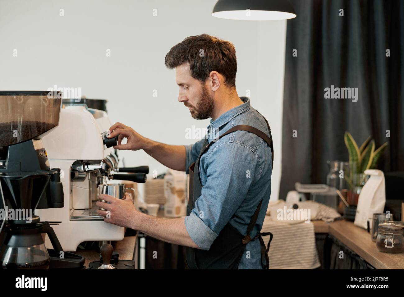 homme barista fouetter du lait à la vapeur de la machine dans le pichet Banque D'Images