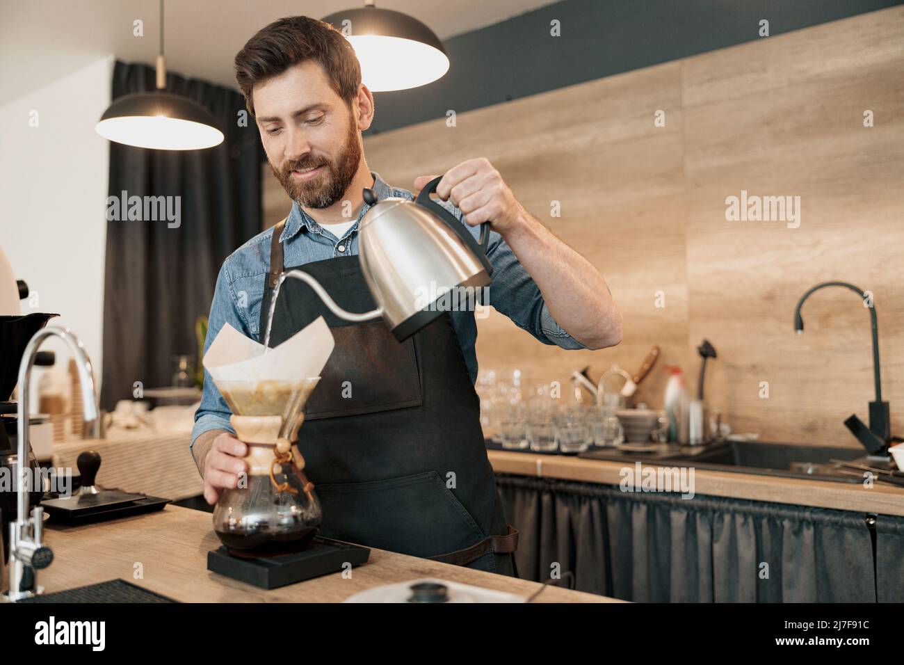 Le barista verse de l'eau pour préparer le café à l'aide d'une machine à café à égoutter manuelle Banque D'Images