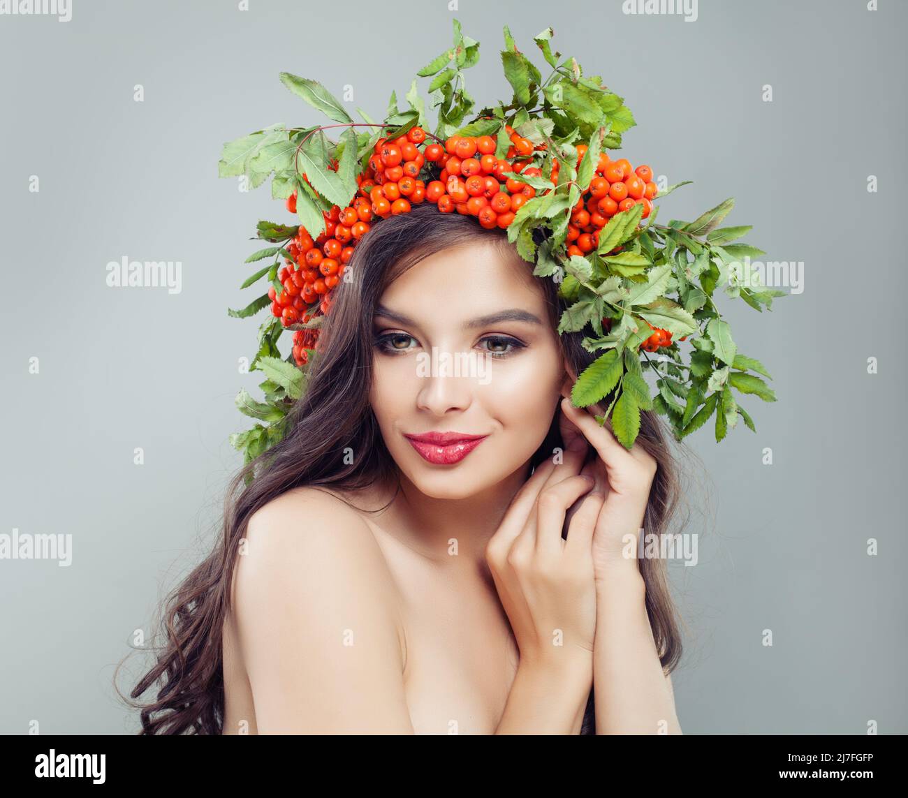 Belle femme avec maquillage, cheveux de curly foncé et baies de rovan dans ses cheveux Banque D'Images