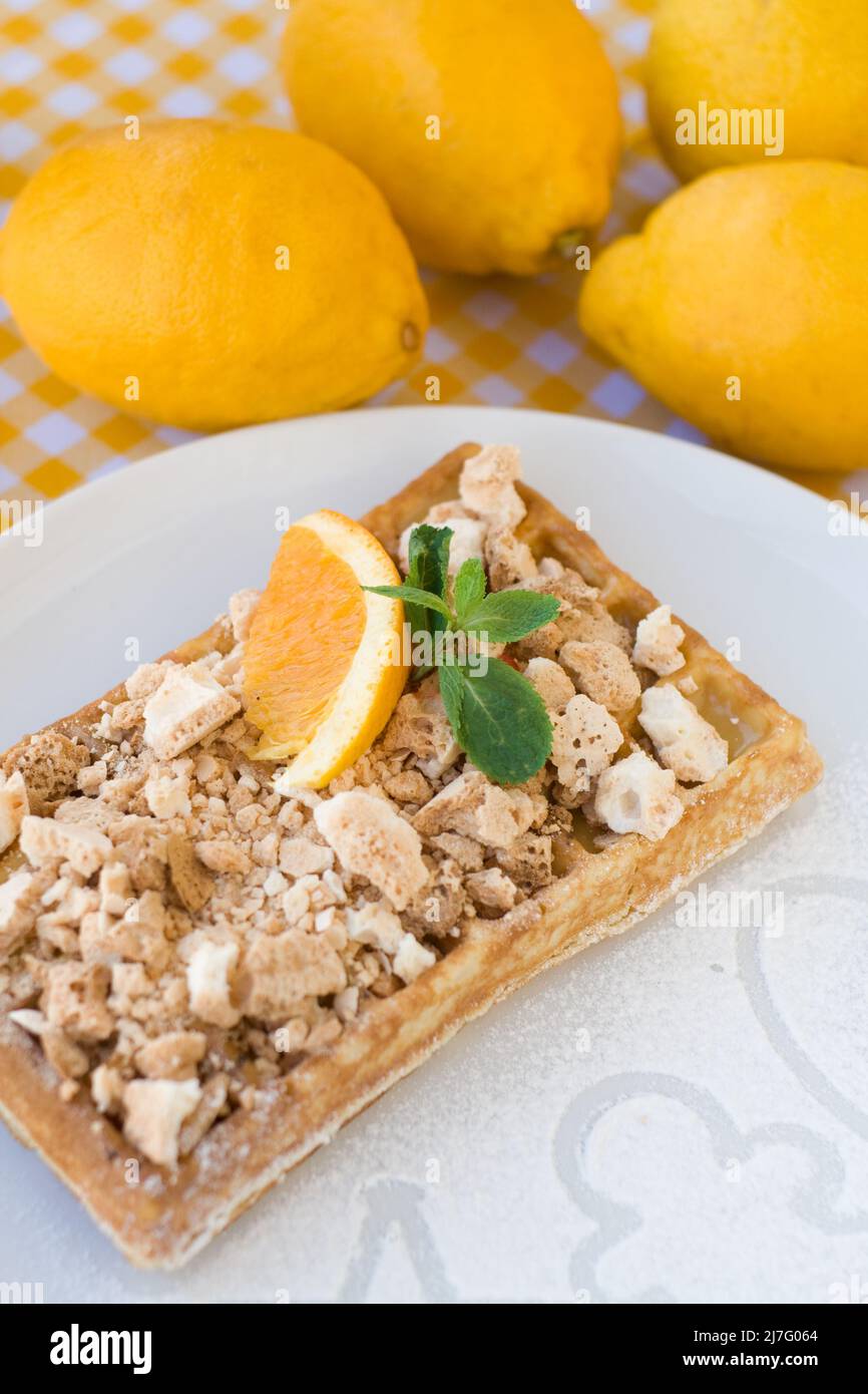 Gaufres avec meringue, boucles de citron et tranches d'orange pour le petit déjeuner Banque D'Images