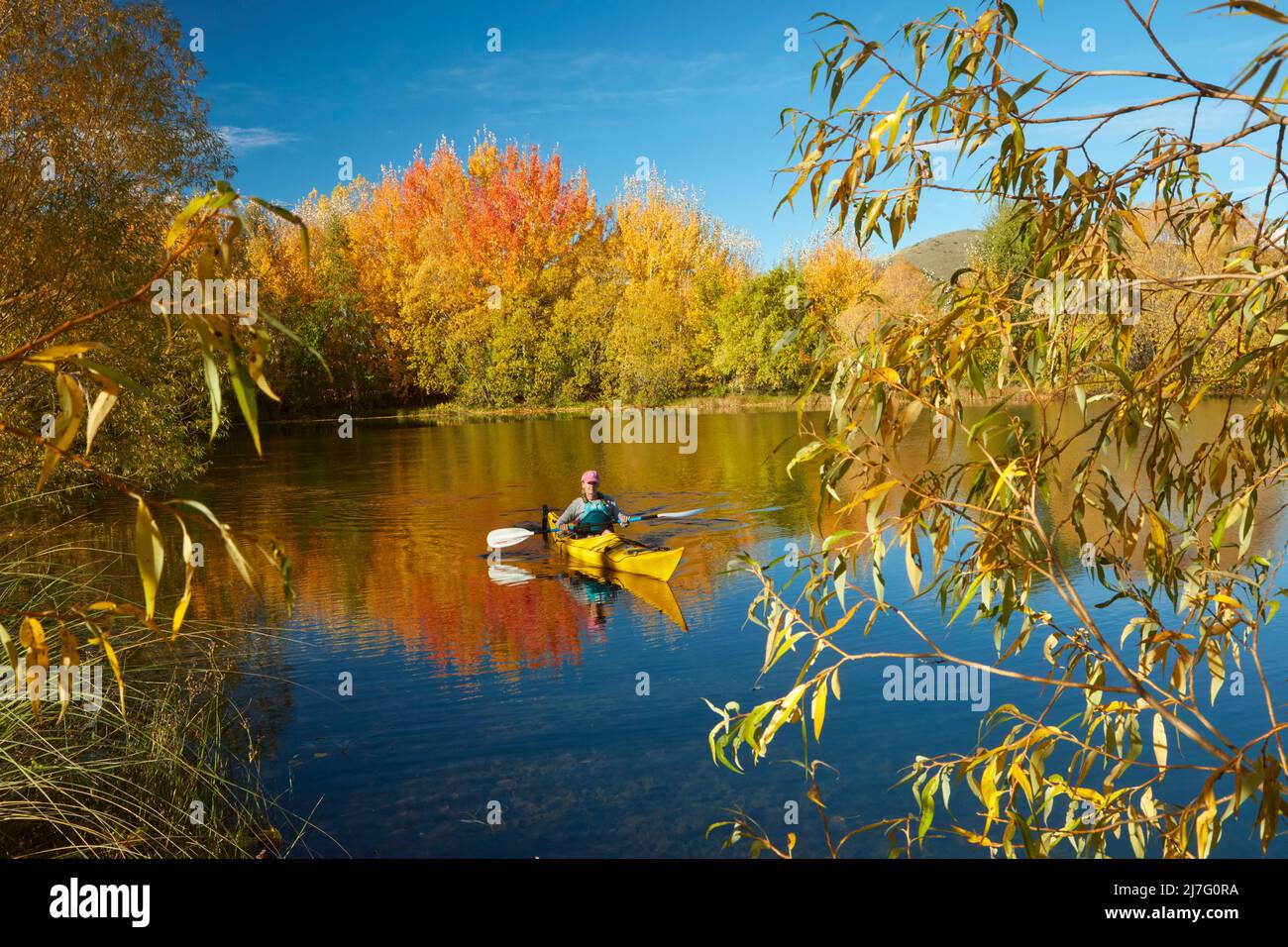 Kayak et réflexions automnales dans l'étang de Kellands, près de Twizel, district de Mackenzie, North Otago, South Island, Nouvelle-Zélande (lancement du modèle) Banque D'Images