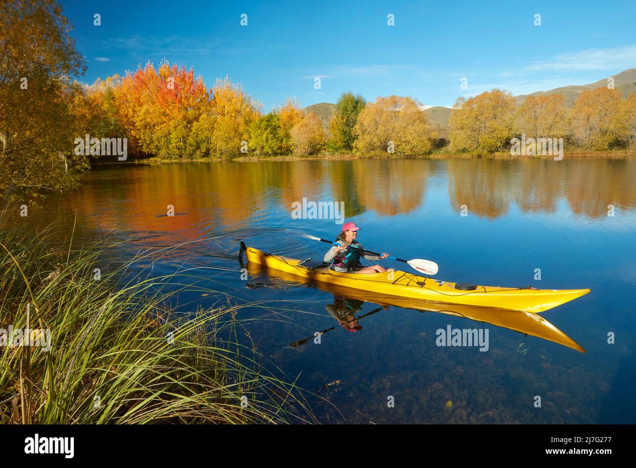 Kayak et réflexions automnales dans l'étang de Kellands, près de Twizel, district de Mackenzie, North Otago, South Island, Nouvelle-Zélande (lancement du modèle) Banque D'Images