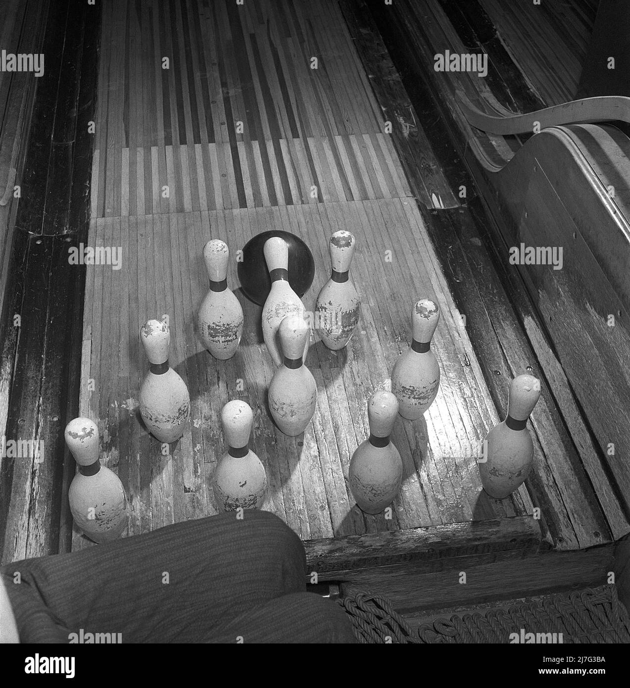 Bowling dans le 1950s. Une photo prise dans la zone de la voie où les quilles sont exactement au moment où la boule de bowling frappe les quilles. Pour le moment, cette piste de bowling n'a pas de machines qui soulèvent les quilles. Au lieu de cela, les gens ont été employés comme des raiseurs de broche et les jambes d'une telle personne est vu comme il a ses jambes dans l'air pour éviter d'être heurté par la boule de bowling ou les broches. 1950. Suède Kristoffersson réf. AY35-11 Banque D'Images