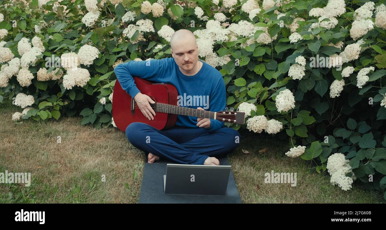 Man in avec guitare dans la nature du parc est en streaming podcast en  ligne à l'aide de gadgets Photo Stock - Alamy