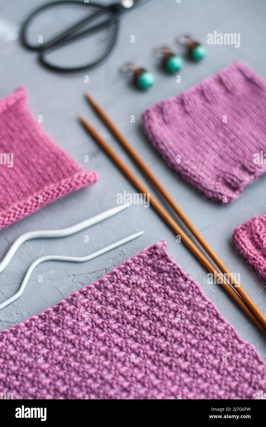 Vue de dessus: Les accessoires de tricotage et les échantillons de produits tricotés se trouvent sur un fond en béton gris. Lieu d'inscription. Banque D'Images