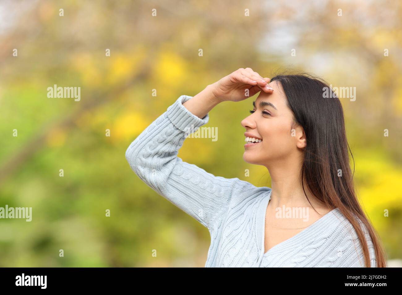 Bonne femme à la recherche avec la main sur le front debout dans un parc Banque D'Images