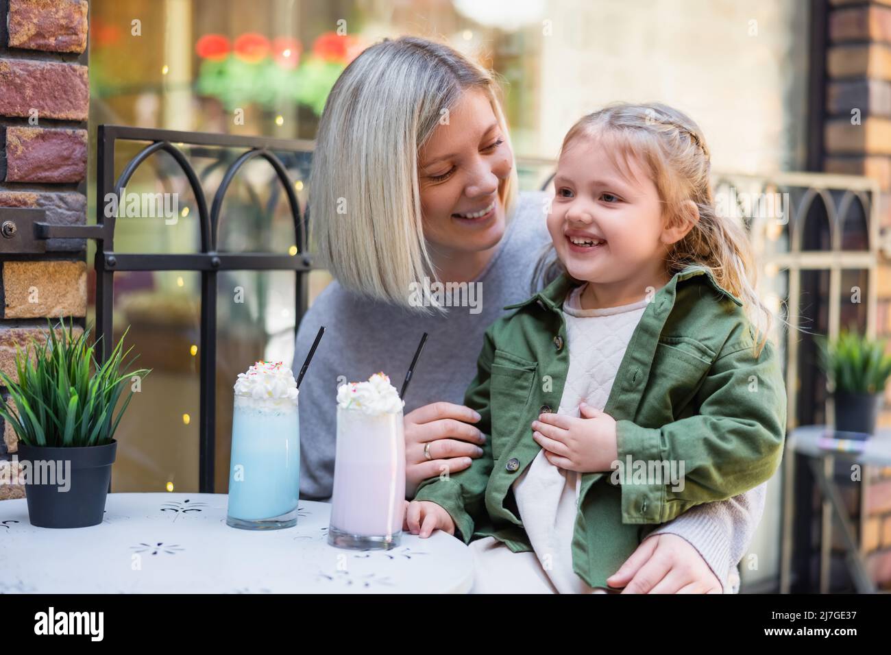 fille heureuse touchant le ventre près des verres avec un délicieux milkshake et maman Banque D'Images