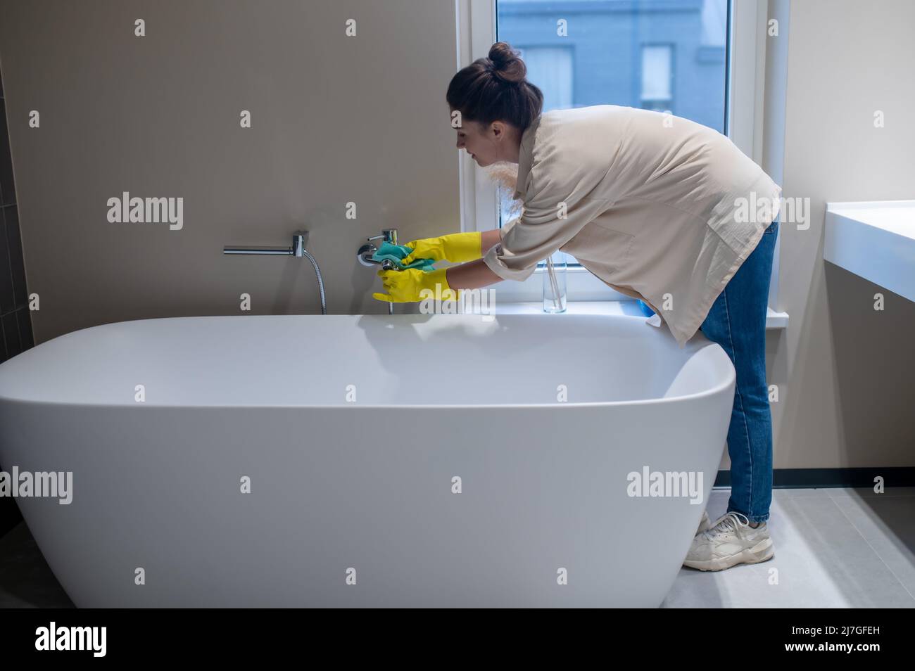 Une femme de ménage désinfectant la salle de bains à la maison Banque D'Images