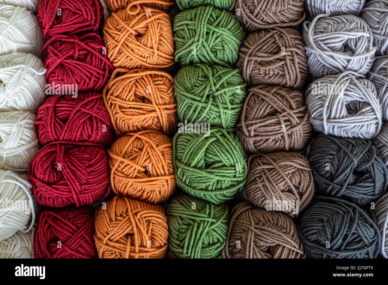 Boules de laine colorées sur une table en bois. Variété de balles en fil, vue d'en haut. Banque D'Images