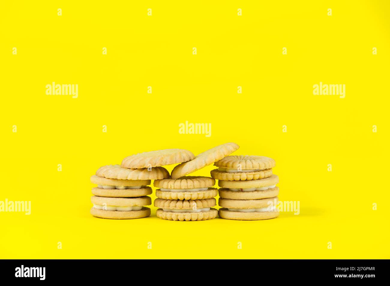 Des piles de biscuits cookies sur un fond jaune vif pour le style de vie malsain régime gain et perte de poids Banque D'Images