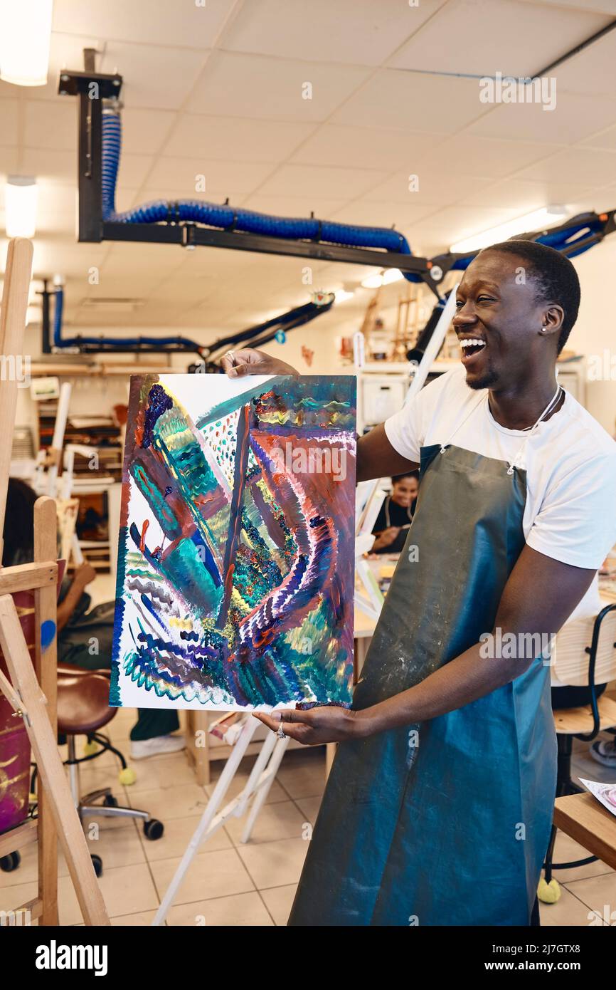 Jeune homme joyeux montrant de la peinture en classe d'art Banque D'Images