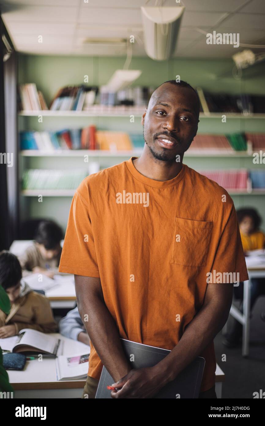 Professeur en t-shirt orange debout en classe Banque D'Images