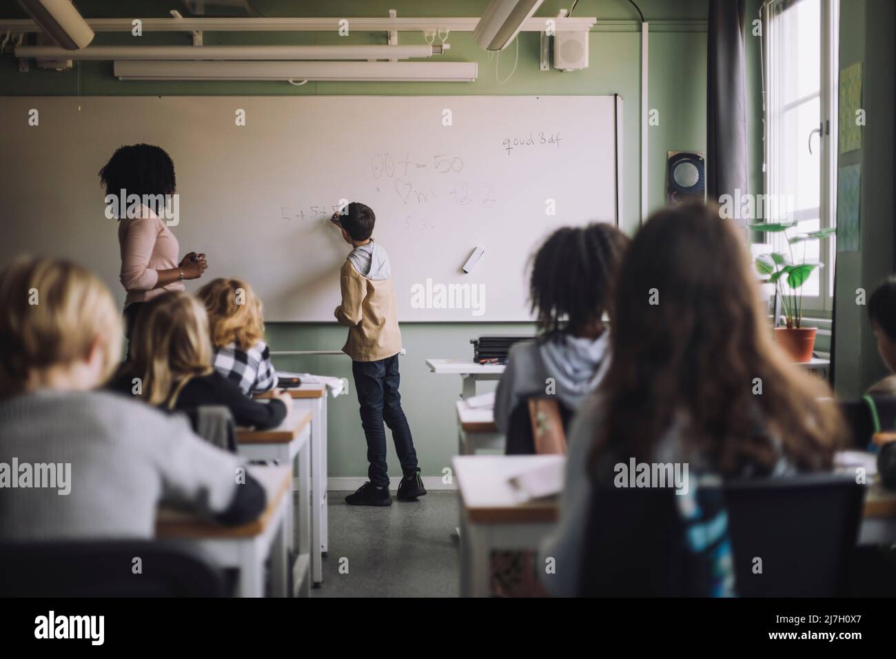 Étudiant résolvant la somme mathématique sur tableau blanc en classe Banque D'Images