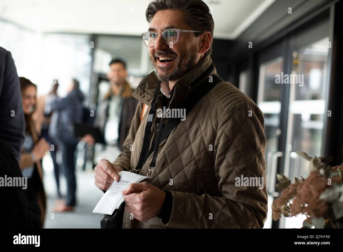 Homme d'affaires heureux montrant une carte d'identité au centre de conférence Banque D'Images