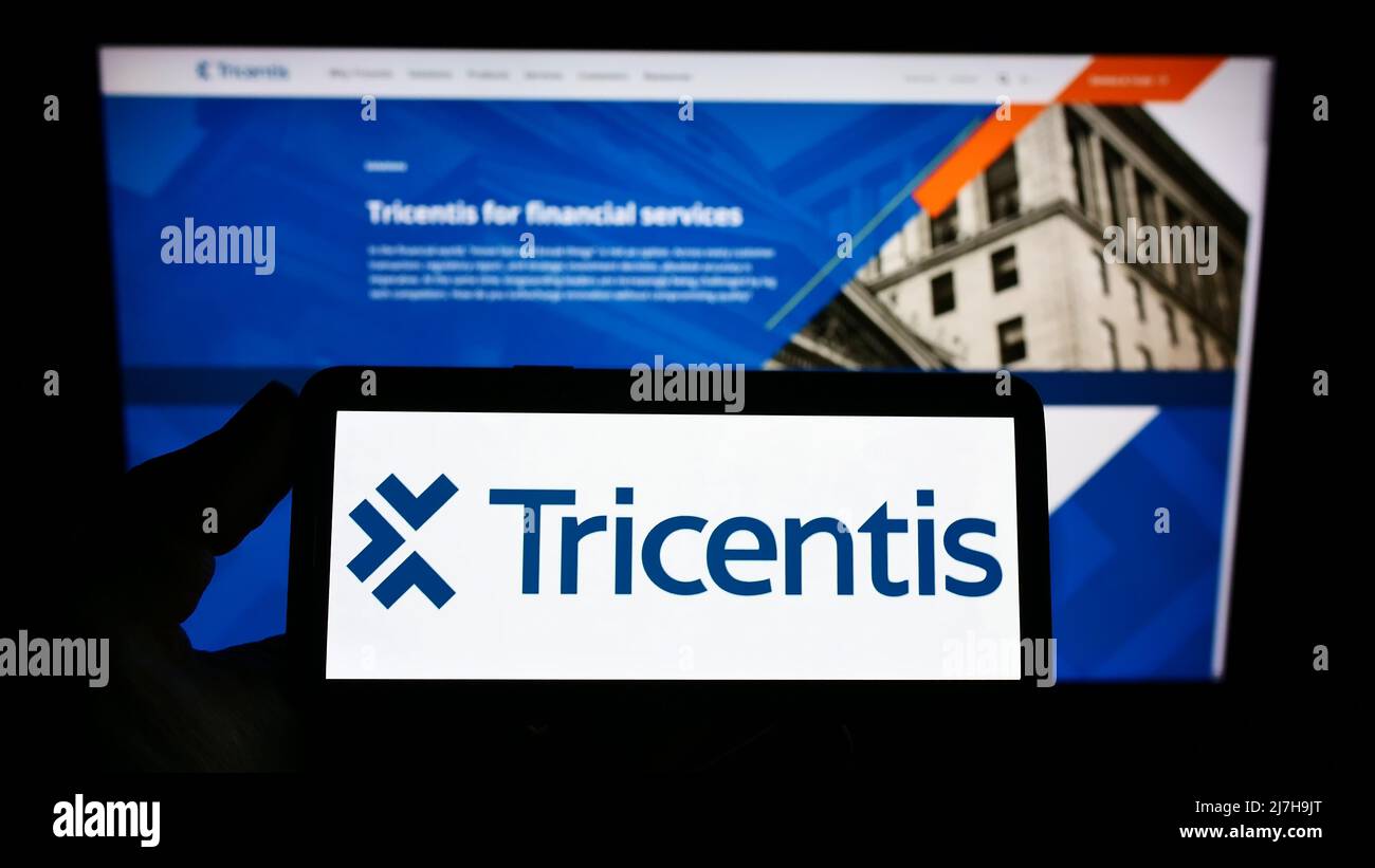 Personne tenant un smartphone avec le logo de la société autrichienne de logiciels Tricentis GmbH sur l'écran devant le site Web. Mise au point sur l'affichage du téléphone. Banque D'Images