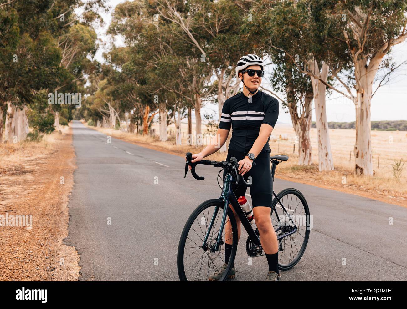 Cycliste femme equipee d une tenue professionnelle pour se detendre a l exterieur. Sportswoman debout sur une route vide avec velo professionnel Photo Stock Alamy