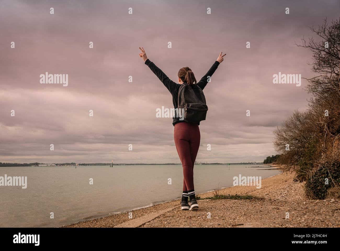 Randonnée réussie avec bras étirés au bord de l'eau. Fond de ciel spectaculaire. Banque D'Images