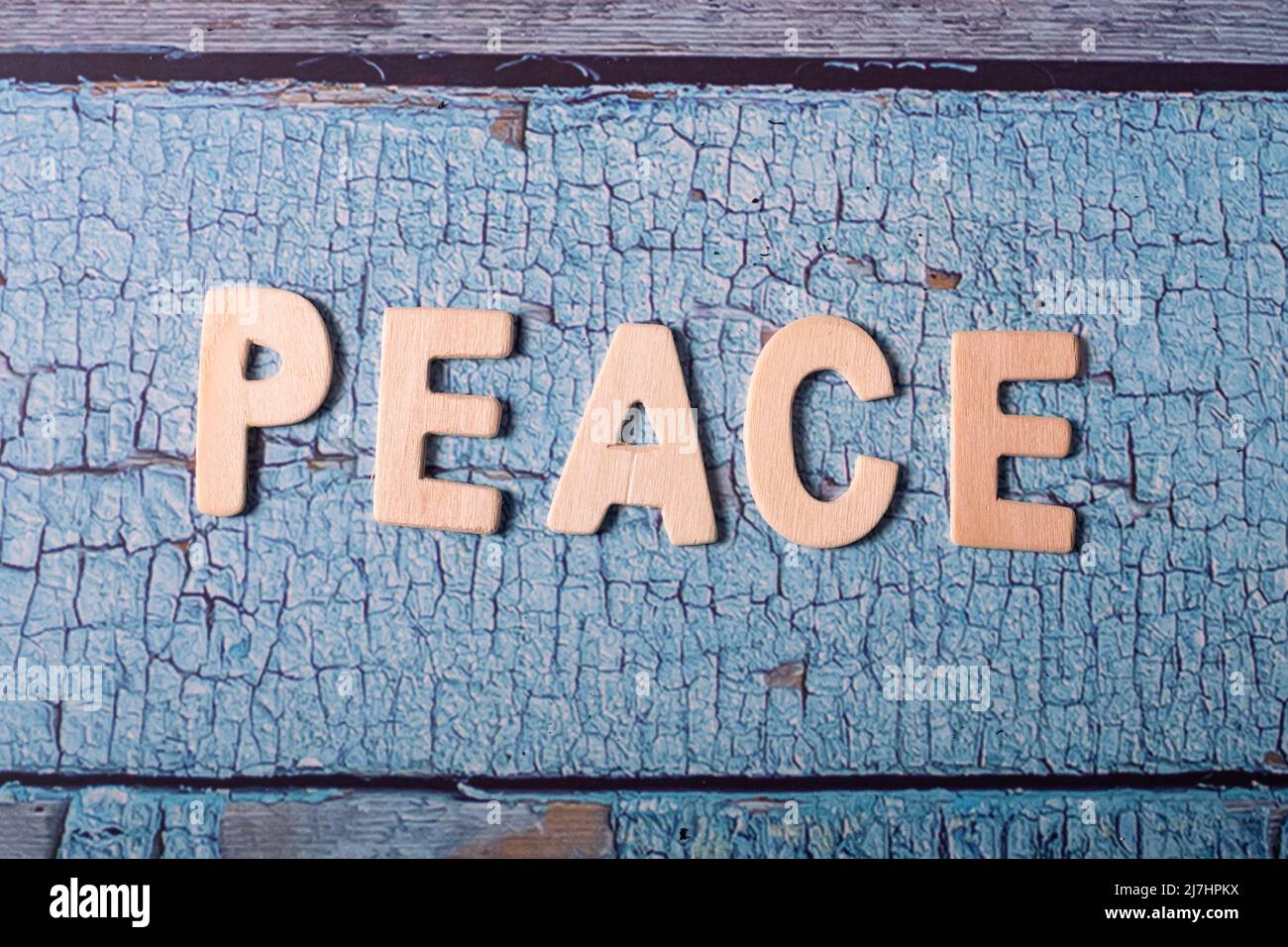 Mot de paix écrit sur des lettres en bois sur fond bleu texturé Banque D'Images