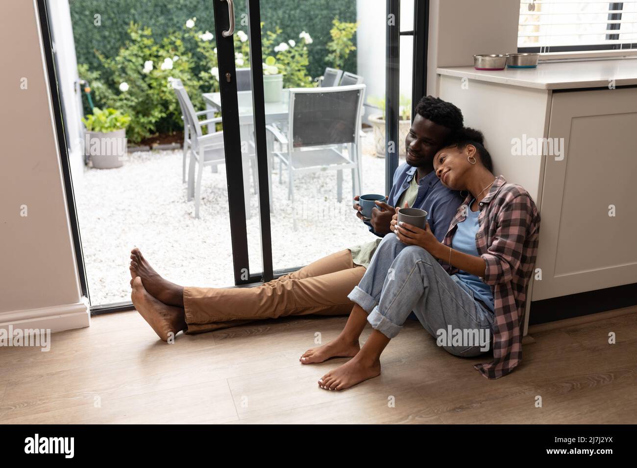 Une jeune femme afro-américaine se repose la tête sur l'épaule du jeune ami tout en prenant un café à la maison Banque D'Images