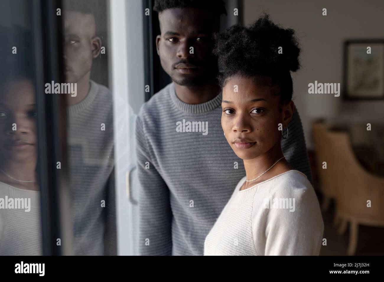 Portrait d'une petite amie afro-américaine sérieuse avec un petit ami debout par la fenêtre à la maison Banque D'Images
