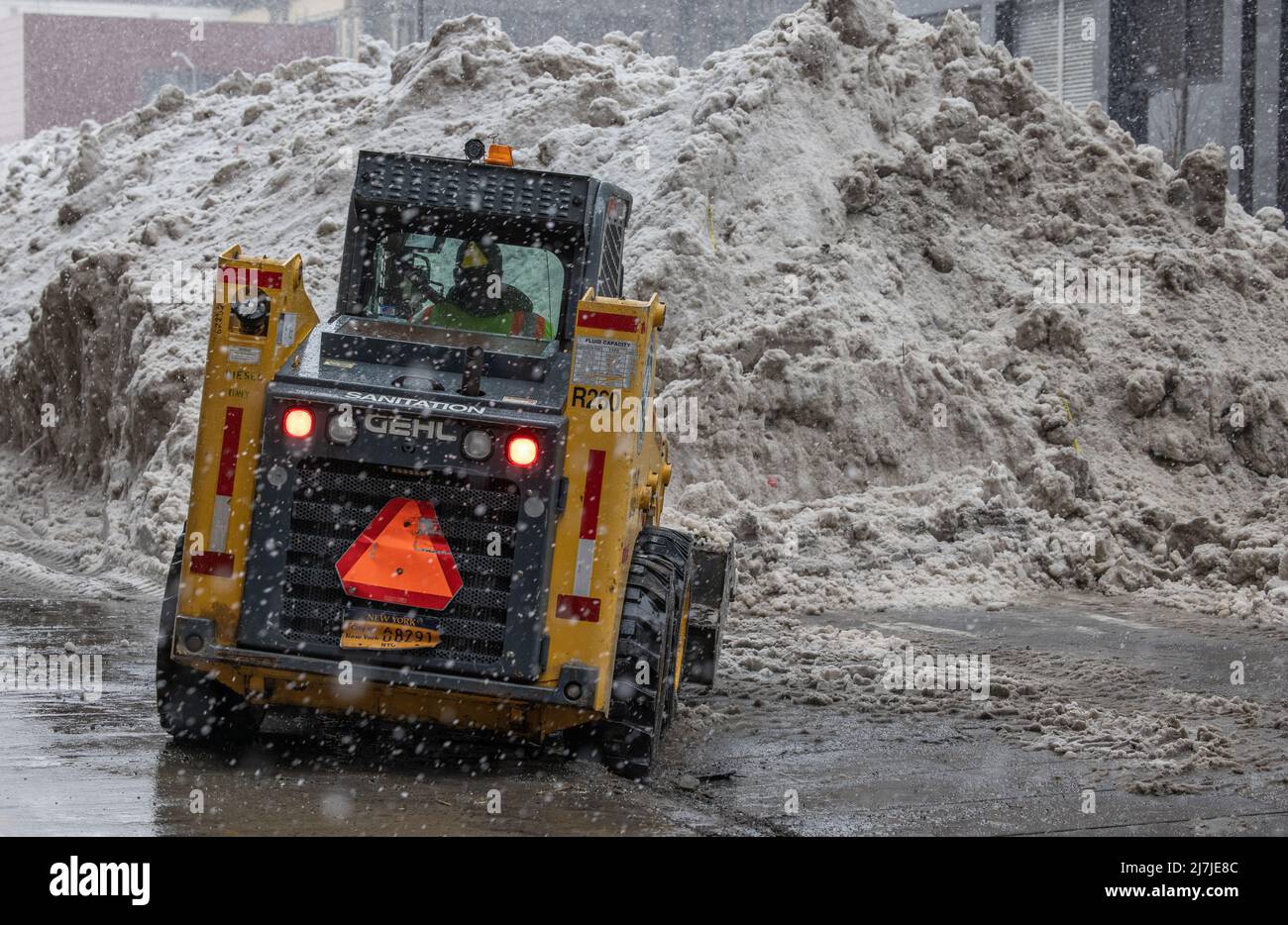 NEW YORK, New York – le 7 février 2021 : un conducteur exploite un véhicule du département de l'assainissement de la ville de New York près d'un dépôt de neige à Lower Manhattan. Banque D'Images
