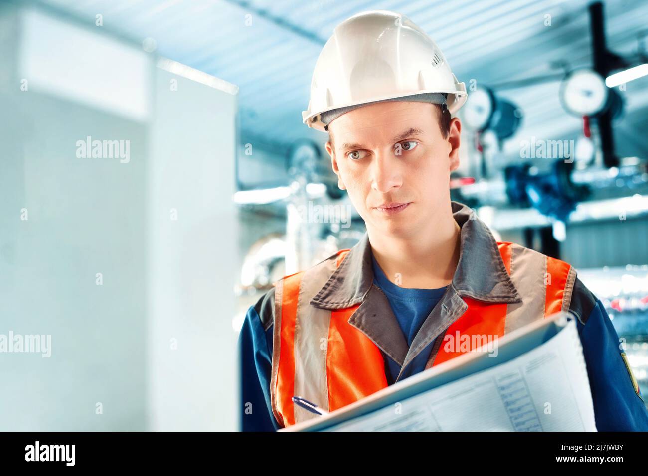 Le jeune ingénieur du casque et du gilet de protection enregistre les relevés des appareils ou de la consommation de gaz dans la chaufferie. Début de la saison de chauffage et approvisionnement en gaz. Banque D'Images