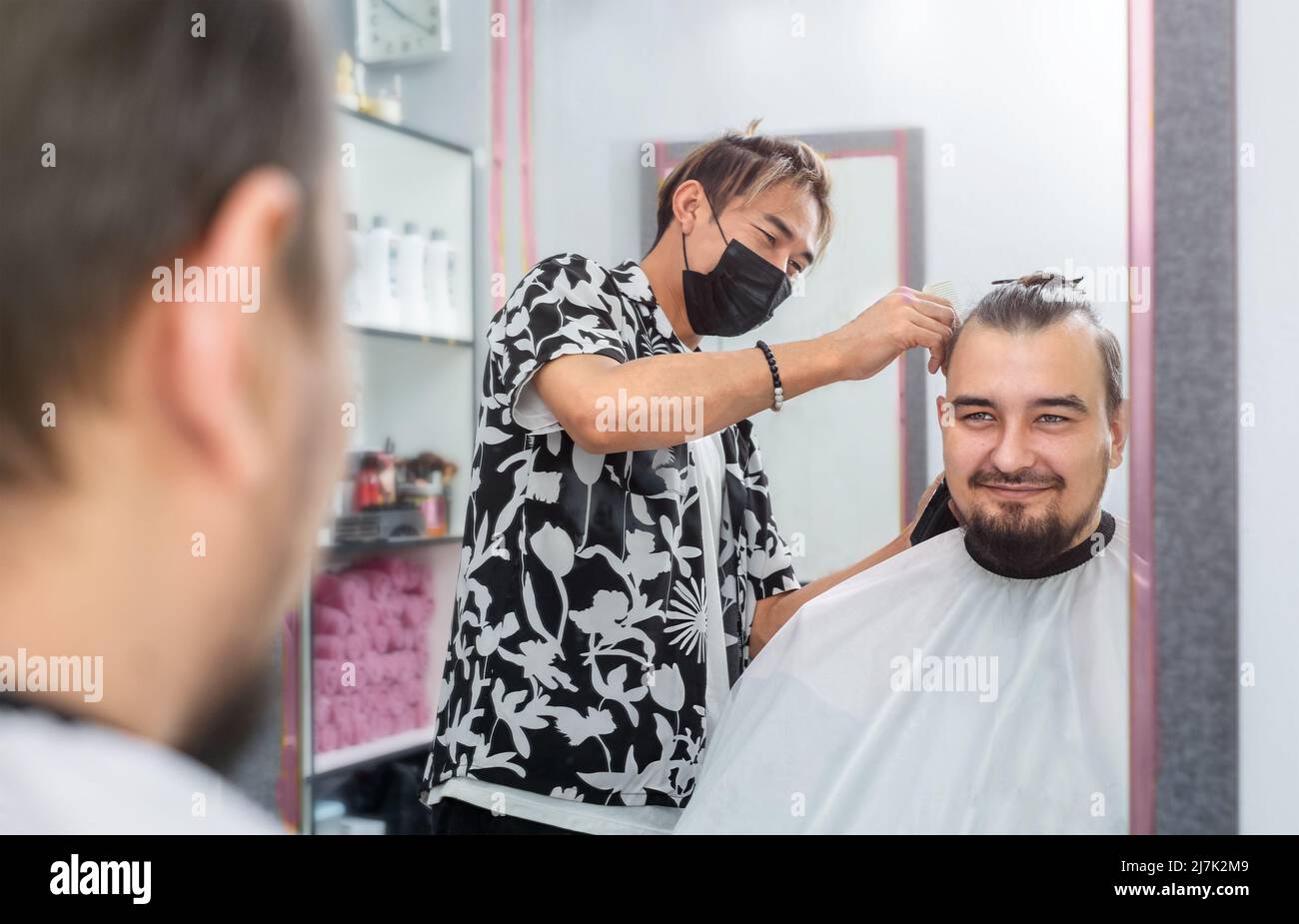 Le coiffeur coupe les cheveux de l'homme dans la barbershop sur le miruw Banque D'Images