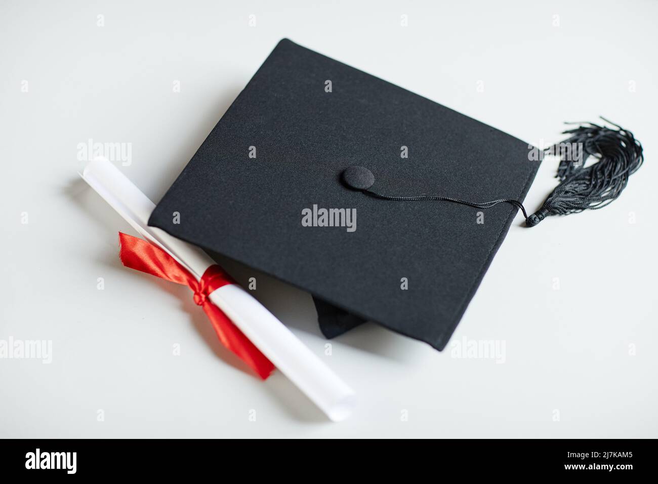Gros plan de la remise des diplômes et du diplôme avec ruban rouge sur fond blanc Banque D'Images
