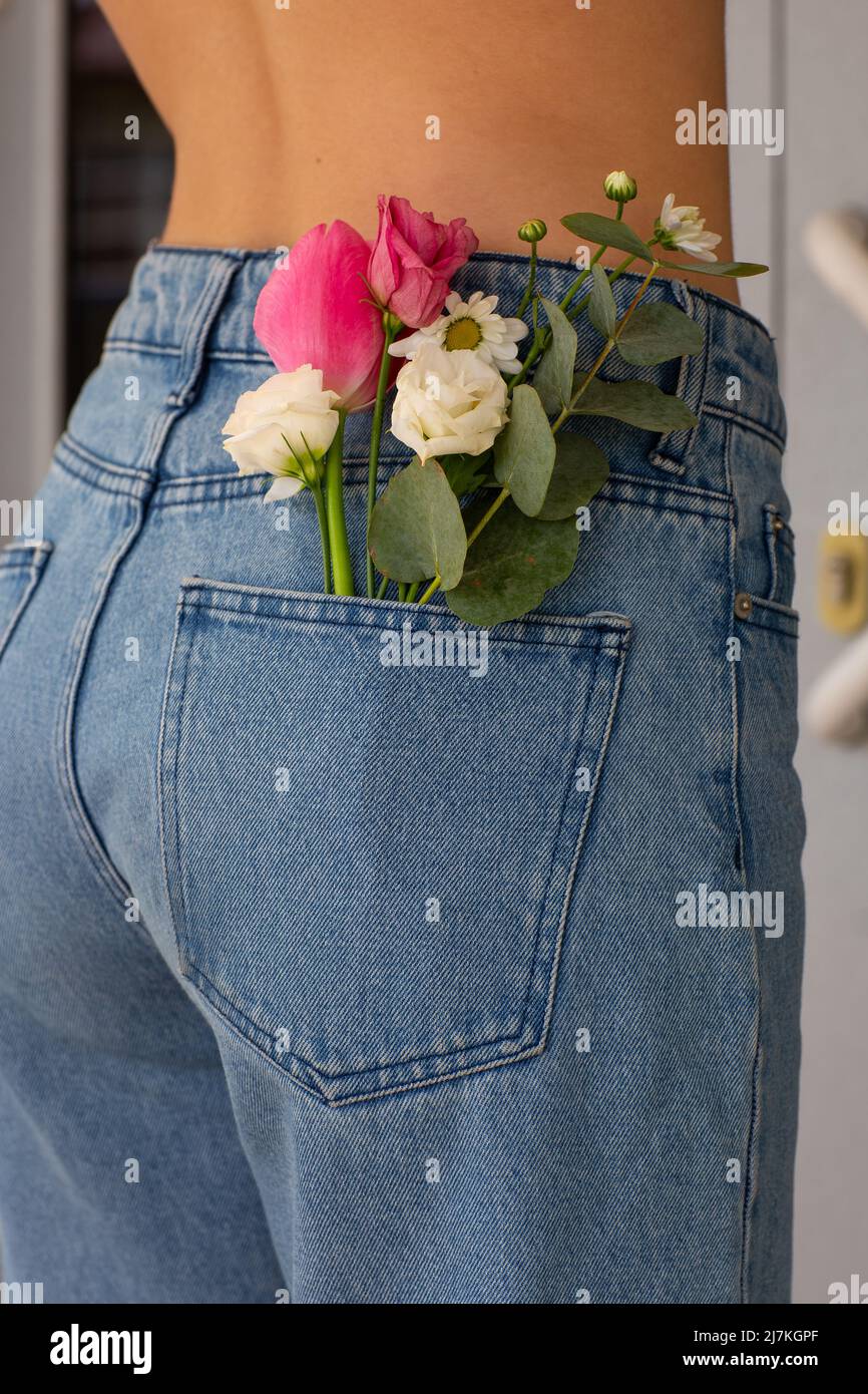 Femme avec de belles fleurs tendres dans la poche arrière du Jean. Une  femme se ramène à l'appareil photo. Un petit bouquet de fleurs de champ  dans une poche arrière de la