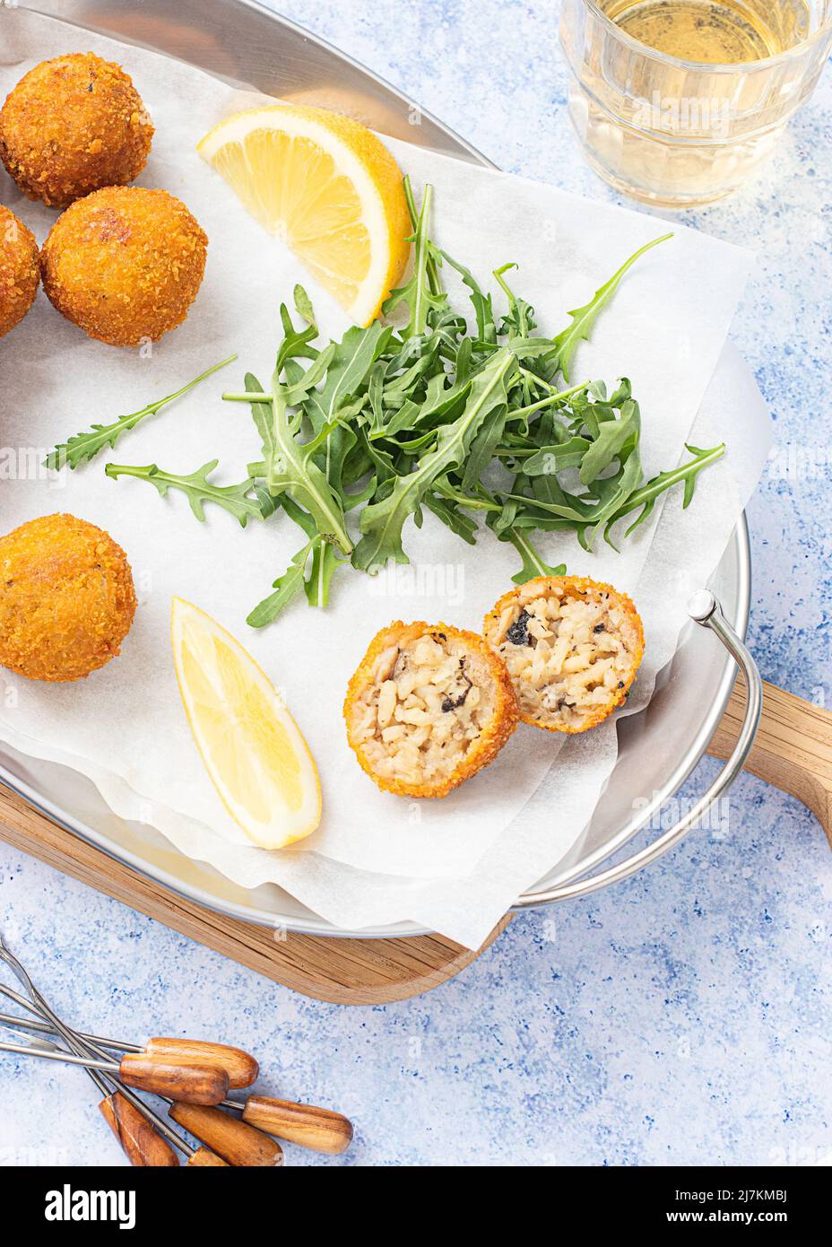 Vue de dessus des boules de riz Arancini placées sur un plateau métallique sur la table avec du citron et des couverts Banque D'Images