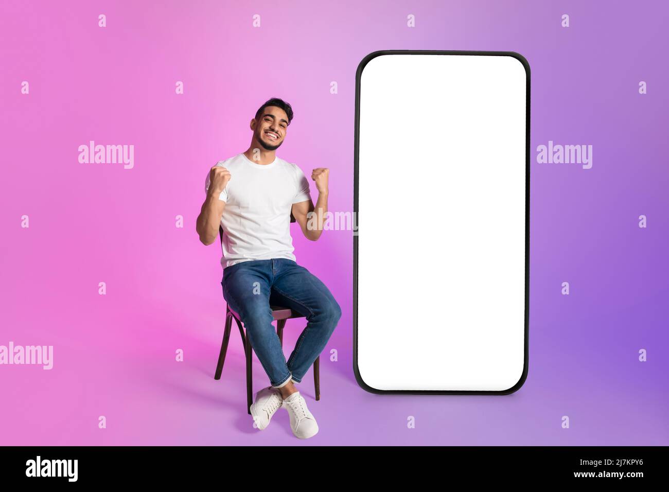 Jeune homme arabe offrant un énorme smartphone avec mockup, gesturant OUI, publicité de magasin Web, casino ou application de loterie Banque D'Images