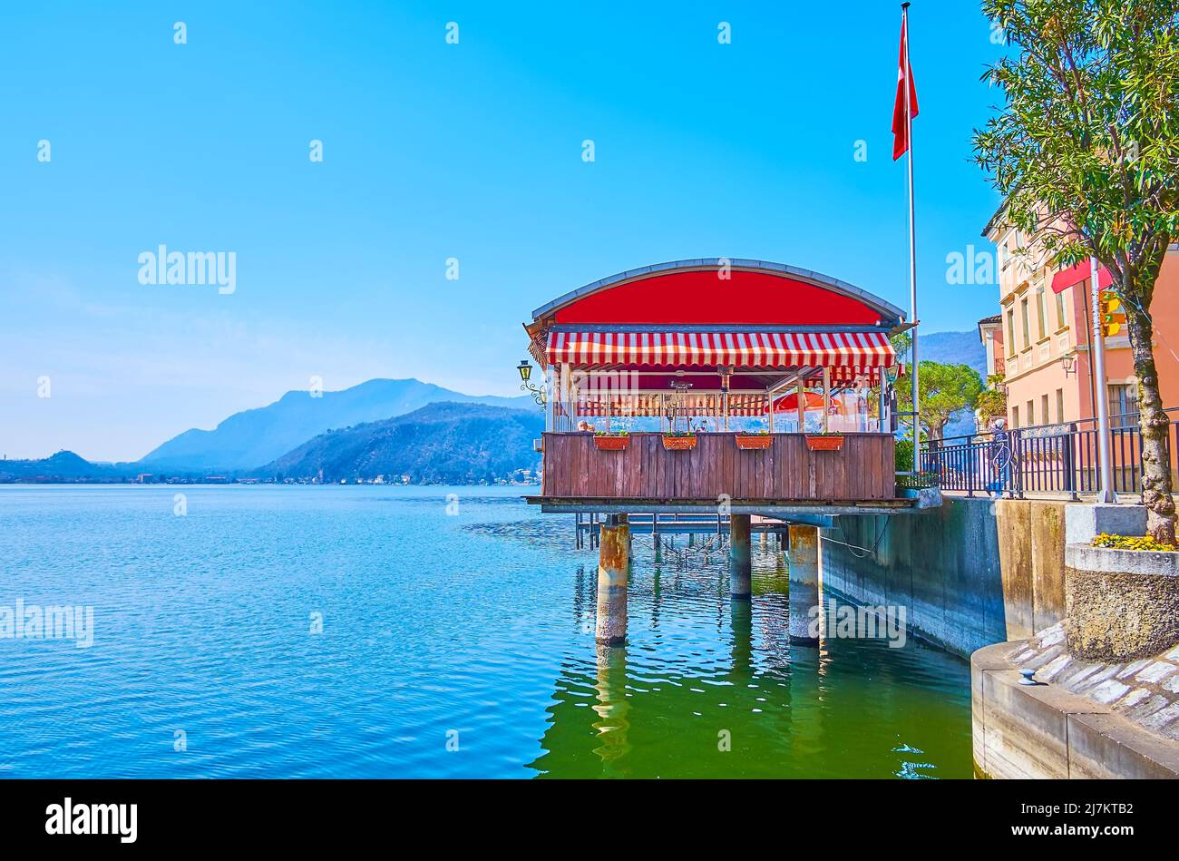 Le pittoresque lac de Lugano, entouré de montagnes et de maisons colorées de Morcote, avec une vue sur le petit pavillon de restaurant sur pilotis à l'avant Banque D'Images
