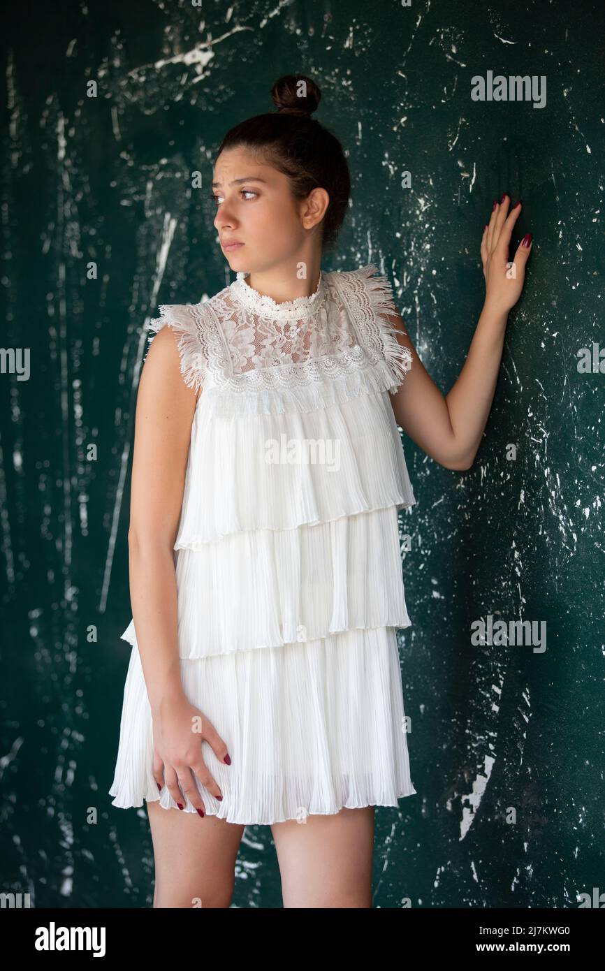 Triste femme en robe blanche courte debout près du mur Banque D'Images