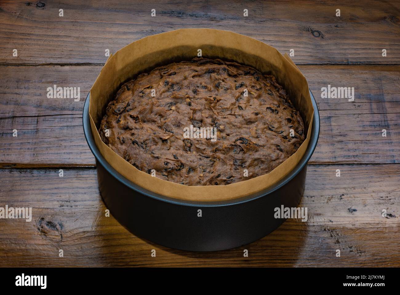 Petit coup de touche d'un gâteau de fruits frais refroidi dans son moule, sur une surface de travail en bois. Banque D'Images