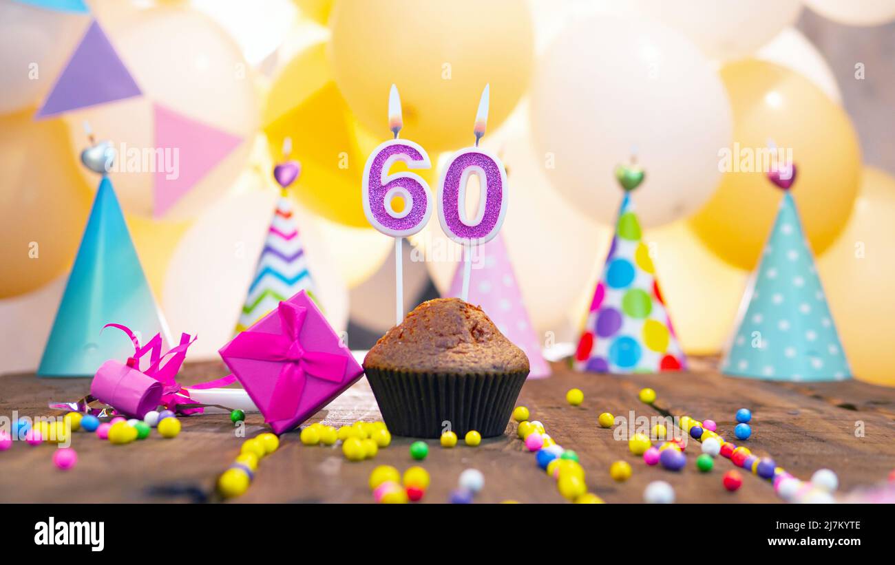 Joyeux anniversaire avec des bougies sur fond de ballons. Un muffin festif aux bougies allumées et une boîte cadeau rose pour une fille. Joyeux anniversaire fille Banque D'Images