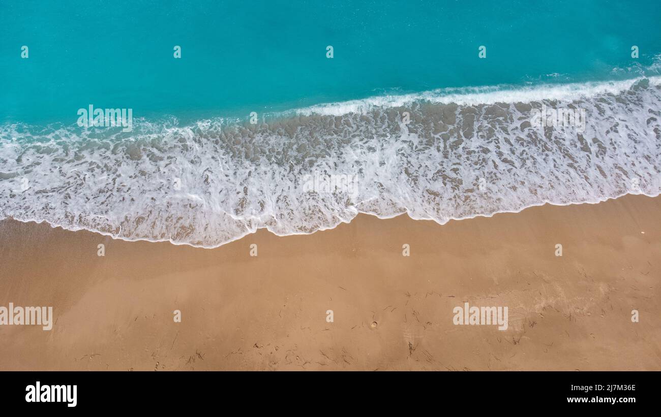 Vue aérienne de la magnifique plage de sable et de la douce vague de l'océan turquoise. Mer tropicale en été sur la plage Megali Petra sur l'île de Lefkada. Banque D'Images