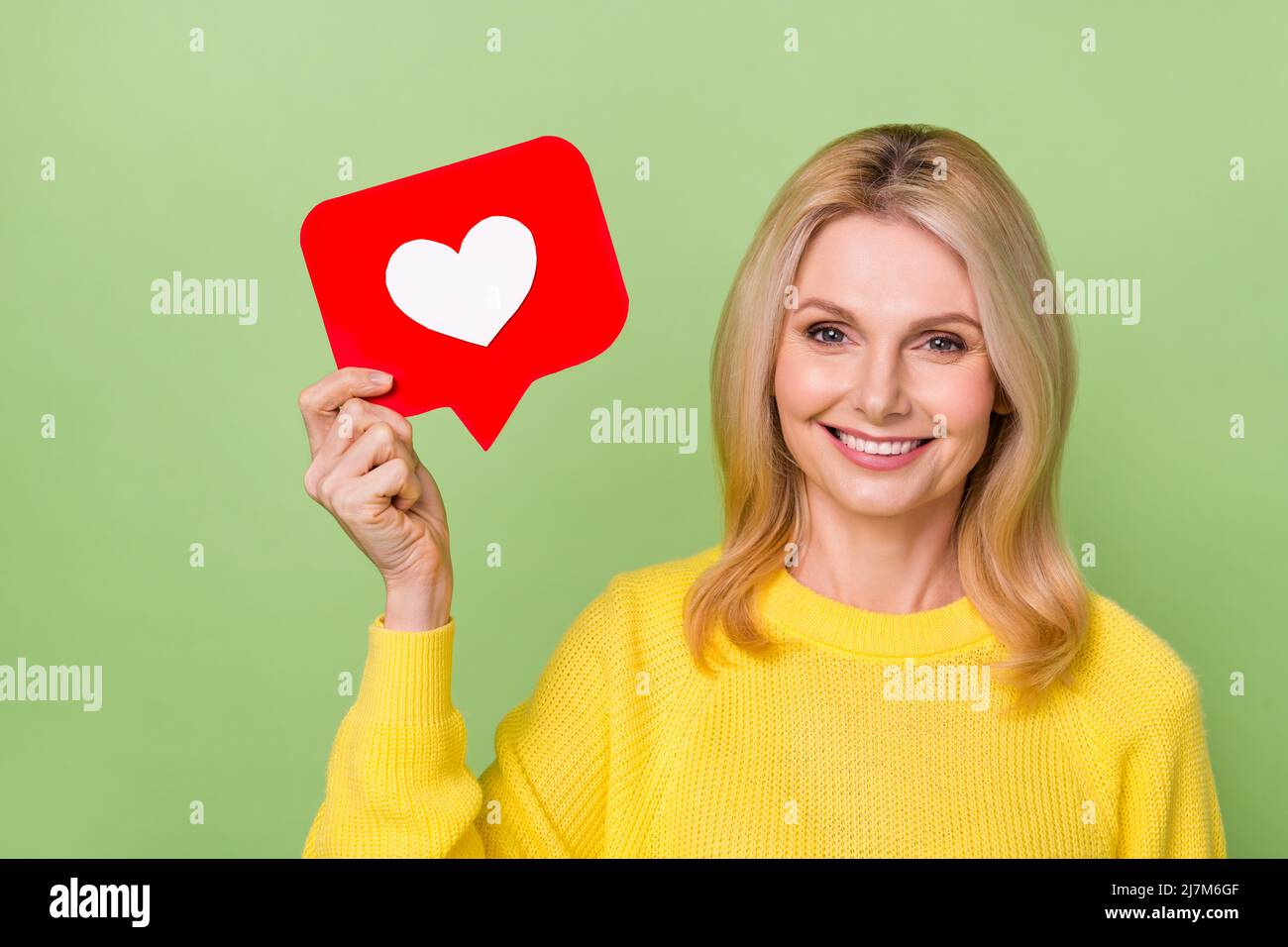 Photo d'une dame âgée blogger tenir papier coeur icône commentaire disciples rétroaction isolé couleur vert arrière-plan Banque D'Images