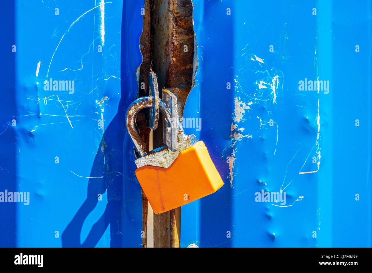 Ancien cadenas orange sur une grille métallique bleue Banque D'Images