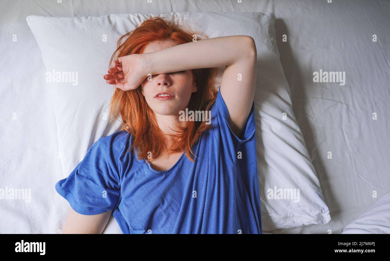 femme couché au lit avec migraine et sensibilité à la lumière recouvrant ses yeux Banque D'Images