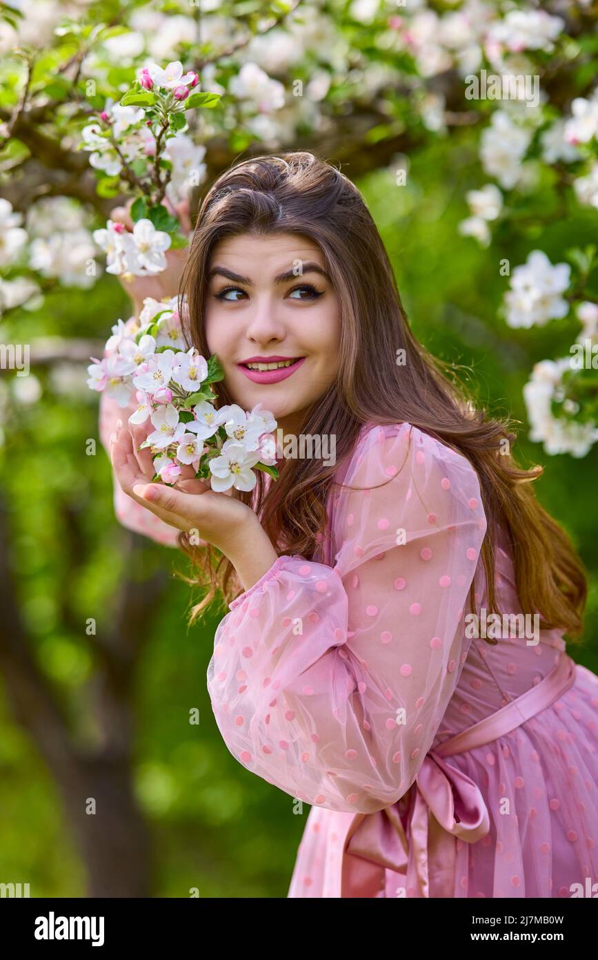 une jeune femme en robe rose posant à côté d'une pomme en fleur, portrait  de printemps Photo Stock - Alamy