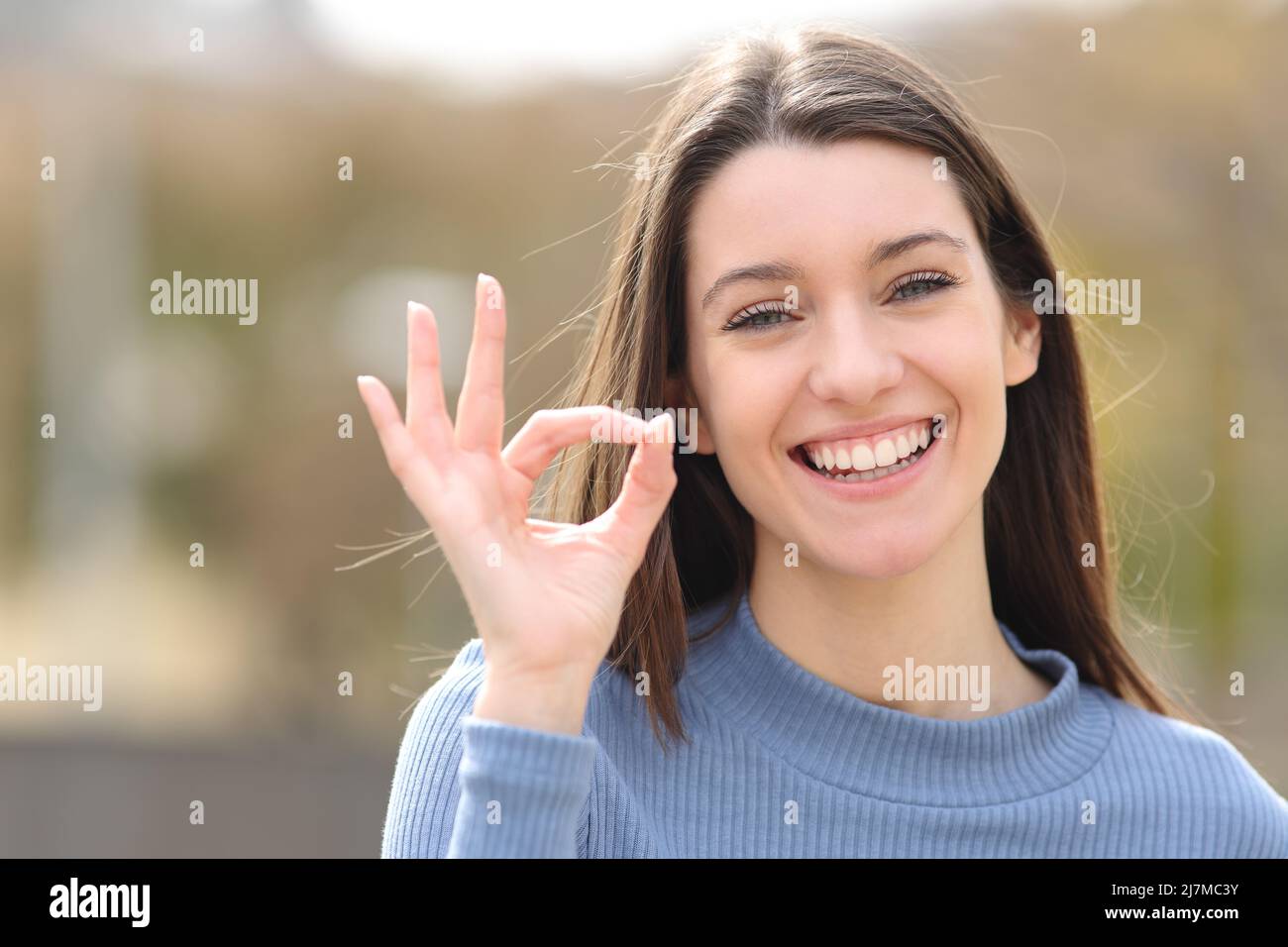 Vue de face portrait d'un adolescent heureux gesturant ok signe dans un parc Banque D'Images