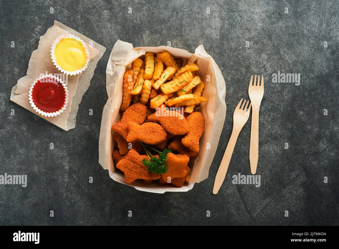 Fish and Chips, restauration rapide britannique. Bâtonnets de poisson avec frites sur une plaque de papier à emporter sur fond de béton ancien sombre. Traditionnel anglais authe Banque D'Images
