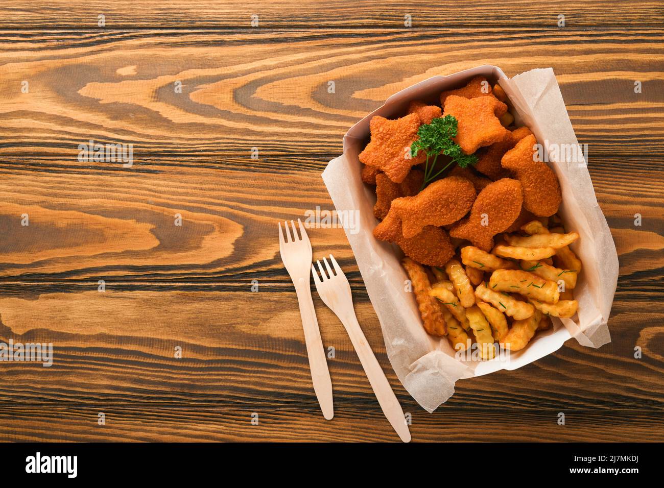 Fish and Chips, restauration rapide britannique. Bâtonnets de poisson avec frites sur une assiette en papier à emporter sur un fond de table en bois. Traditionnel anglais Banque D'Images