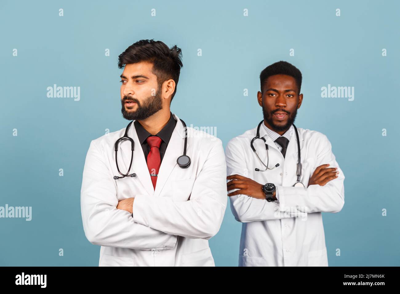 portrait de przloseup d'un professionnel de la santé intellectuel avec un laque blanc discutant des résultats avec un jeune médecin sur fond bleu Banque D'Images