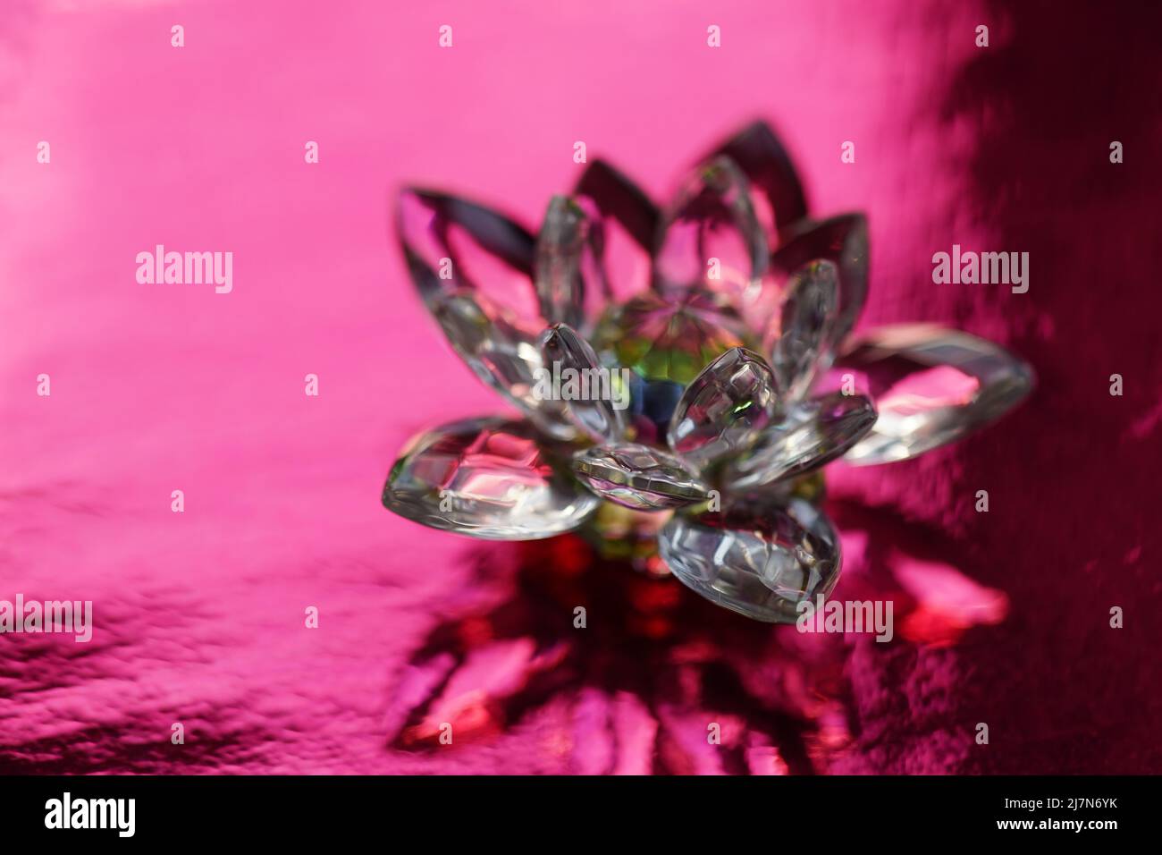 Lotus cristal sur table rouge avec réflexion de lumière. Symbole chakra de Muladhara. Ésotérique, énergie reiki, méditation, guérison spirituelle Banque D'Images