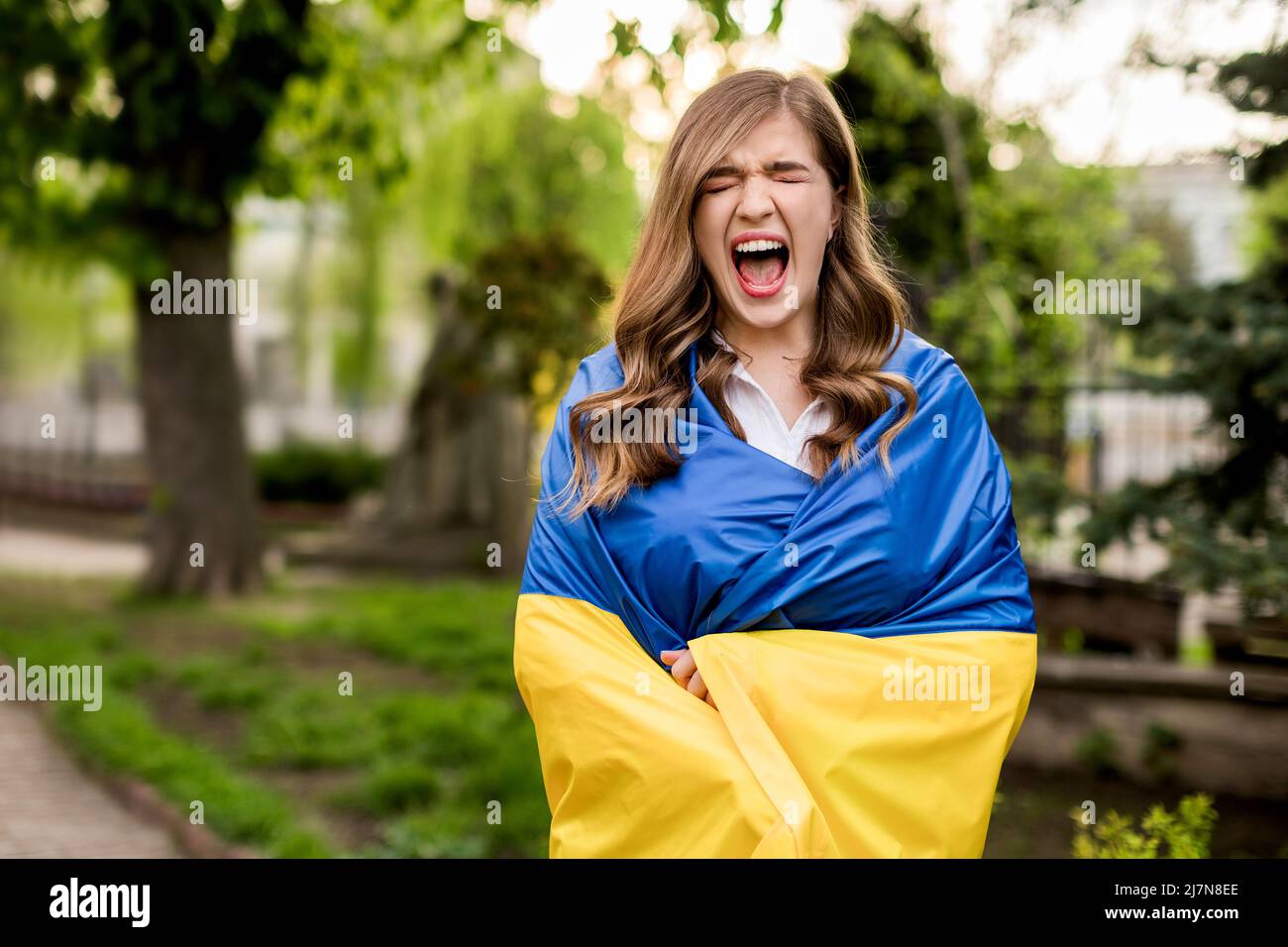 Criant fille debout dans le drapeau ukrainien inquiet au sujet de la guerre. La jeune femme ressent une douleur émotionnelle après avoir lu les nouvelles. Liberté et patriote de Banque D'Images